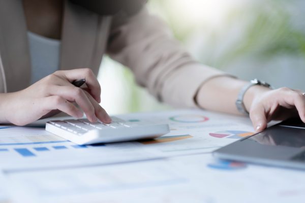 employee accountant woman hand press on calculator for make financial report or company's profit monthly at desk , bookkeeper job and work from home concept.